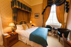 a hotel room with a bed and a desk and a window at Kildonan Lodge Hotel in Edinburgh