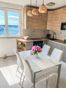 uma cozinha com uma mesa com cadeiras brancas e flores cor-de-rosa em Homey apartment with a view em Split
