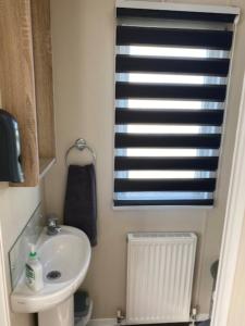 a small bathroom with a sink and a window at Beautiful Spacious Holiday Home - Romney Sands in New Romney
