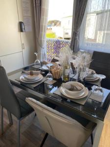 a dining room table with plates and glasses on it at Beautiful Spacious Holiday Home - Romney Sands in New Romney