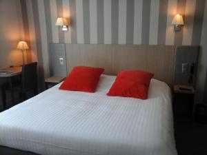 ein Schlafzimmer mit einem Bett mit zwei roten Kissen in der Unterkunft Hôtel Carmin in Le Havre