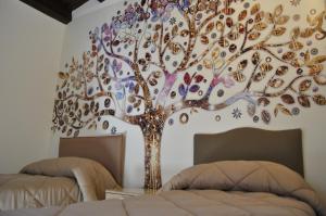 a tree mural on a bedroom wall with two beds at Balconi Bellavista in Cefalù