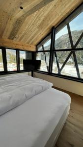a bedroom with a white bed in front of windows at Amus Suites Dolomites in Anterselva di Mezzo