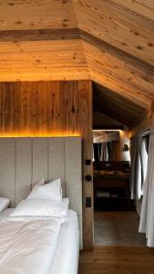 - une chambre avec un lit et un plafond en bois dans l'établissement Amus Suites Dolomites, à Anterselva di Mezzo