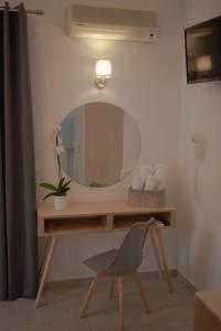 a bathroom with a vanity with a mirror and a chair at ATHANASIA APARTMENTS in Skiathos