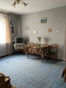 a living room with a table and a tv at Заміський будинок in Rzhyshchiv