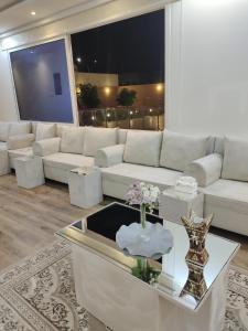 a living room with a white couch and a table at شاليه البستان حي المنتزه الغربي in Hail