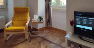 un salon avec une chaise jaune et une télévision dans l'établissement Appartamento storico in zona Barberini, à Rome