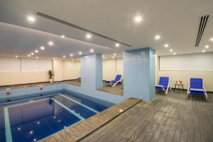 a pool in a room with blue chairs and tables at Enala Hotel - Al Khobar in Al Khobar