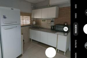 uma cozinha com armários brancos e um frigorífico branco em Cardozo House Monoambiente acogedor y familiar em Villa Dolores