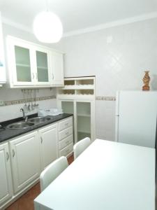 uma cozinha com armários brancos, um lavatório e um frigorífico em VillasMC no Alpalhão