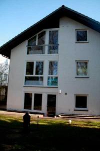 a large white house with a man standing in front of it at Gaestehaus Denecke in Scharbeutz