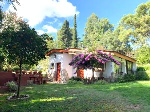 ein kleines Haus mit lila Blumen im Hof in der Unterkunft La Linda de la Aldea Serrana in La Falda