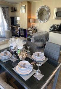 a dining table with plates and wine glasses on it at Beautiful Spacious Holiday Home - Romney Sands in New Romney