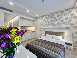 a bedroom with a bed and flowers in a room at Your Sunshine Apartments Batumi in Batumi