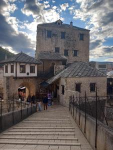 a group of people walking down a bridge in front of a castle at Apartman Miletic in Mostar