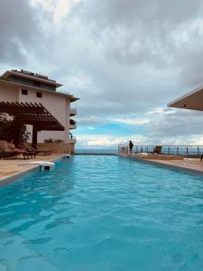 a swimming pool in front of a building with the ocean at Meherio - Bel Appartement vue mer à TAHITI in Papeete