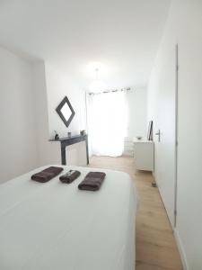 ein weißes Schlafzimmer mit einem Bett mit zwei braunen Handtüchern darauf in der Unterkunft Le 29 spacieux , wifi et climatisation in Agen