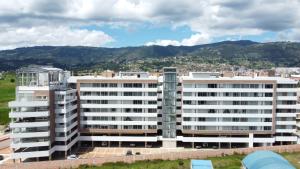 a large white building with mountains in the background at Lujoso Apartamento Cerca al Lago Sochagota en Paipa in Paipa