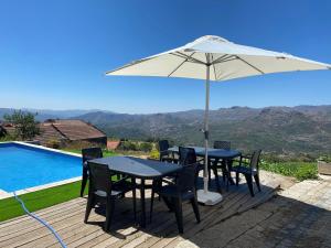 een tafel en stoelen onder een parasol naast een zwembad bij Fraga de Pitões in Pitões das Júnias