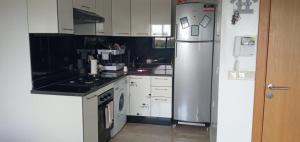 uma cozinha com armários brancos e um frigorífico de aço inoxidável em Garden Bay - Appartement en bord de mer em Tamaris