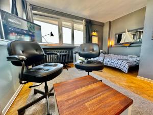- une chambre avec deux chaises, un lit et un bureau dans l'établissement Super Apartament GREY Centrum 2x Metro Fast WiFi 300 Mbs Netflix AppleTV SmartTV Spotify Panorama Miasta, à Varsovie