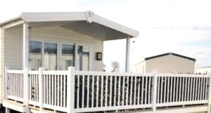 a white porch with a white fence in front of a house at Beautiful Spacious Holiday Home - Romney Sands in New Romney