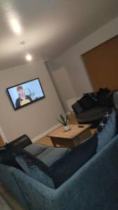a living room with a blue couch and a tv at Meadow View in Moneymore
