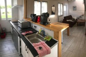 eine Küche mit einem Waschbecken und ein Wohnzimmer in der Unterkunft Maisonnette avec terrasse, jardin et poêle à bois in Pierrefitte-Nestalas