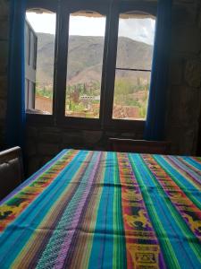 a colorful blanket on a bed in a room with windows at Hospedaje Fortaleza Indigena in Tilcara