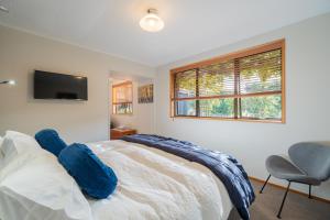 a bedroom with a bed and a tv and a chair at Alpine Rock B&B in Te Anau