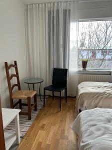 a bedroom with a bed and a chair and a window at Art Guesthouse Olla in Selfoss