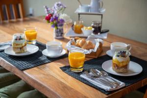 una mesa con alimentos para el desayuno y vasos de zumo de naranja en Alpine Rock B&B, en Te Anau