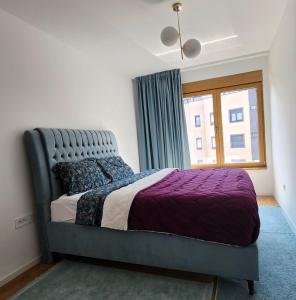 een slaapkamer met een bed met een paarse sprei en een raam bij APARTMAN FLORENCE in Mirijevo