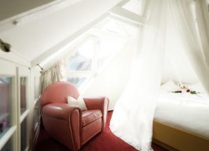 une chaise rouge dans une chambre avec un lit dans l'établissement Romantisches Haus im Schnoor, à Brême