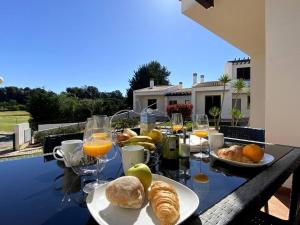 uma mesa com pão, laranjas e copos de sumo de laranja em Golf Villa Alvor By CORAL em Alvor