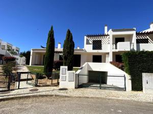 una gran casa blanca con una valla y árboles en Golf Villa Alvor By CORAL, en Alvor