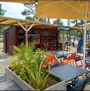 un restaurant avec des tables, des chaises et un parasol dans l'établissement Mobil home Premium Camping 5*, à Vendays-Montalivet