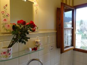 a bathroom with a sink with a vase of flowers on a shelf at Il Nido della Formica in Colonnata