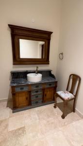 a bathroom with a sink and a chair and a mirror at Casimiro Ibera Hotel Boutique in Colonia Carlos Pellegrini