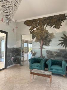 a living room with two blue couches and a tree mural at Casimiro Ibera Hotel Boutique in Colonia Carlos Pellegrini