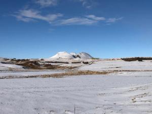 un campo cubierto de nieve con una montaña en el fondo en Guesthouse Húsid en Hlíðarendi
