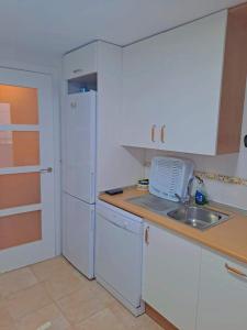 a white kitchen with a sink and a refrigerator at APARTAMENTO MANUELA PROXIMO a GOLF ISLA CANELA LINKS in Ayamonte