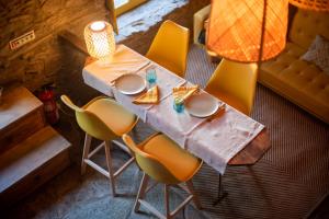 a dining table with yellow chairs and a lamp at Lagos Com Sabor Guest House 