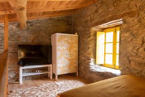 a bedroom with a tv in a stone wall at Lagos Com Sabor Guest House 