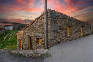 an old stone building with yellow doors and a sunset at Lagos Com Sabor Guest House 