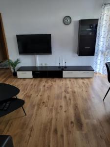 a living room with a flat screen tv and a wooden floor at Ferienwohnung am Bodensee in Tettnang