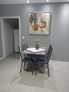 a dining room table with chairs and a painting on the wall at Ótimo apartamento sobreloja com wifi e estacionamento incluso in Maringá