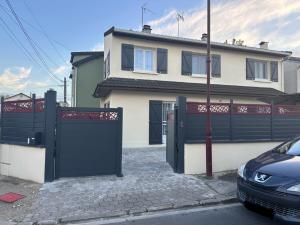 a house with a black gate and a car parked in front at Chambre pour 2 personnes dans la banlieue parisienne (Bondy) in Bondy