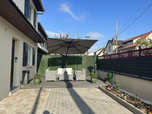 a patio with two white chairs and an umbrella at Chambre pour 2 personnes dans la banlieue parisienne (Bondy) in Bondy
